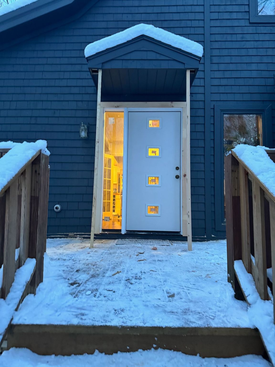 A blue house with a white door and snow on the steps