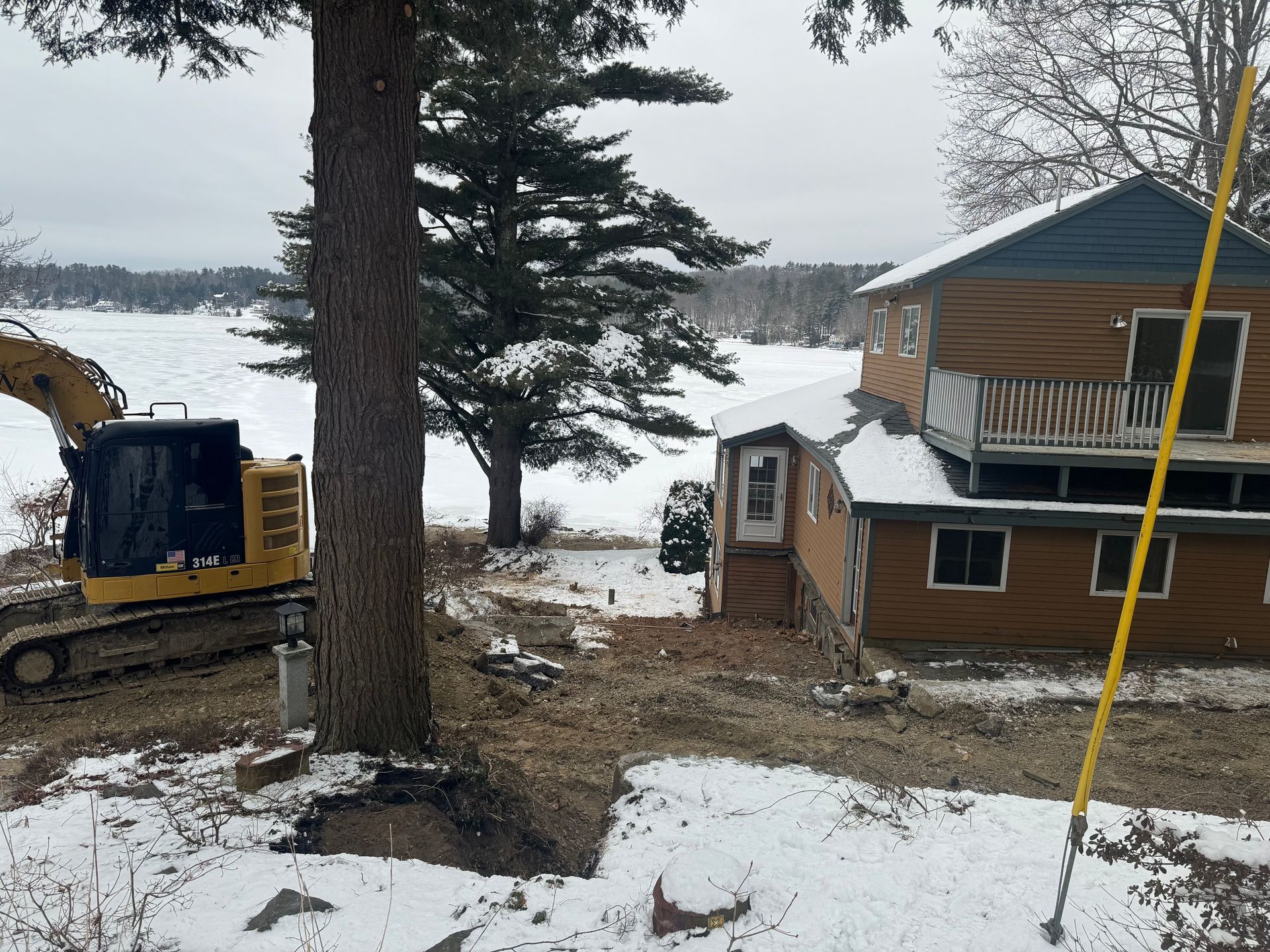 a house with orange siding with a parked excavator next to it in the winter time