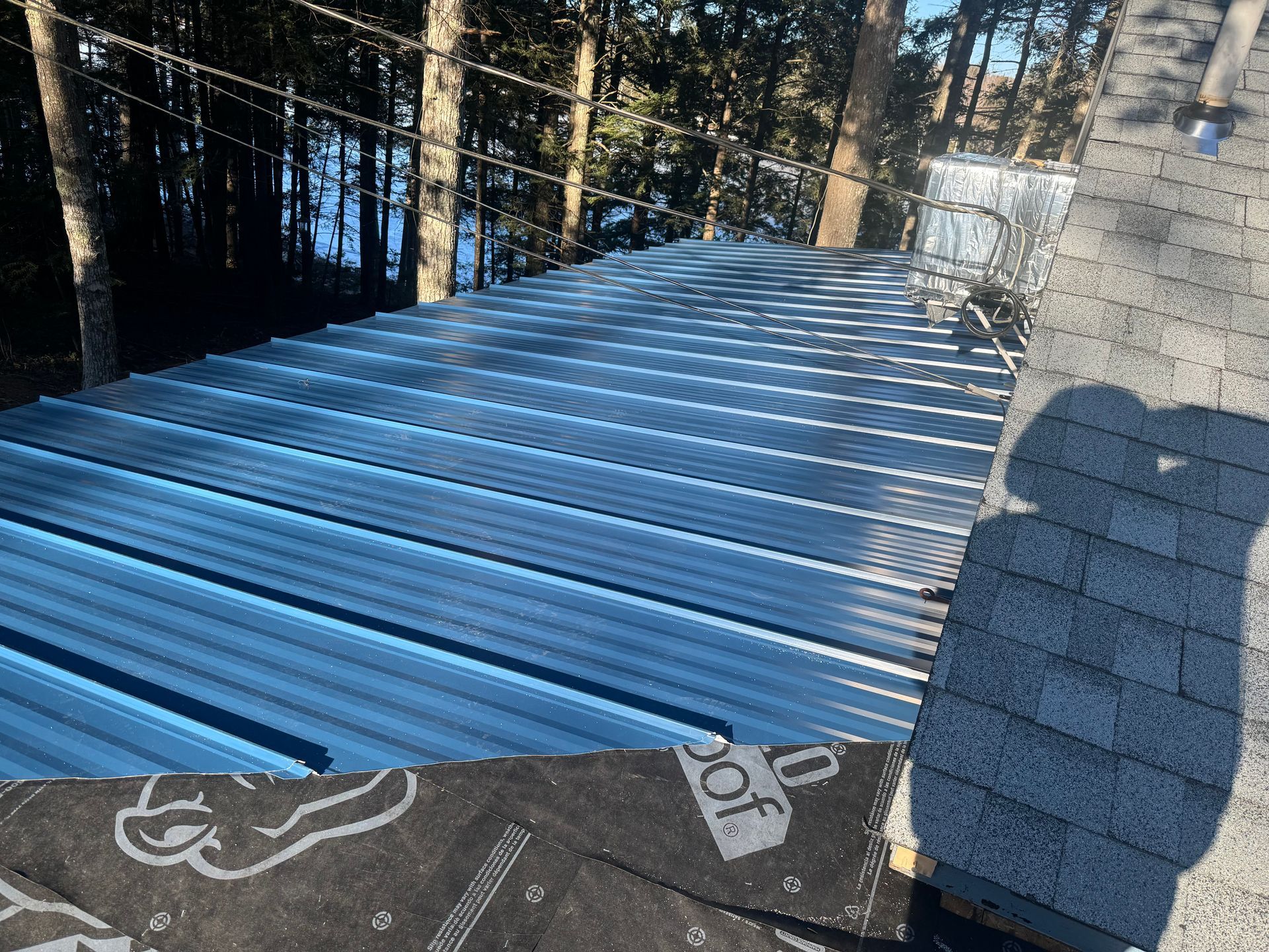 A blue metal roof is being installed on a house.