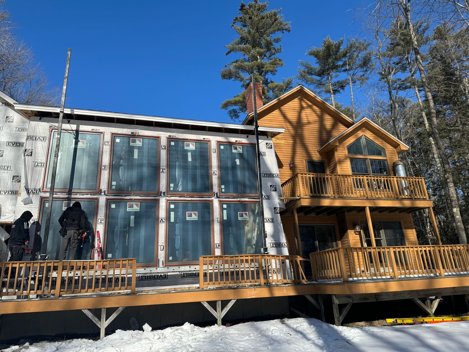 contractors working on a home with a wall of andersen windows