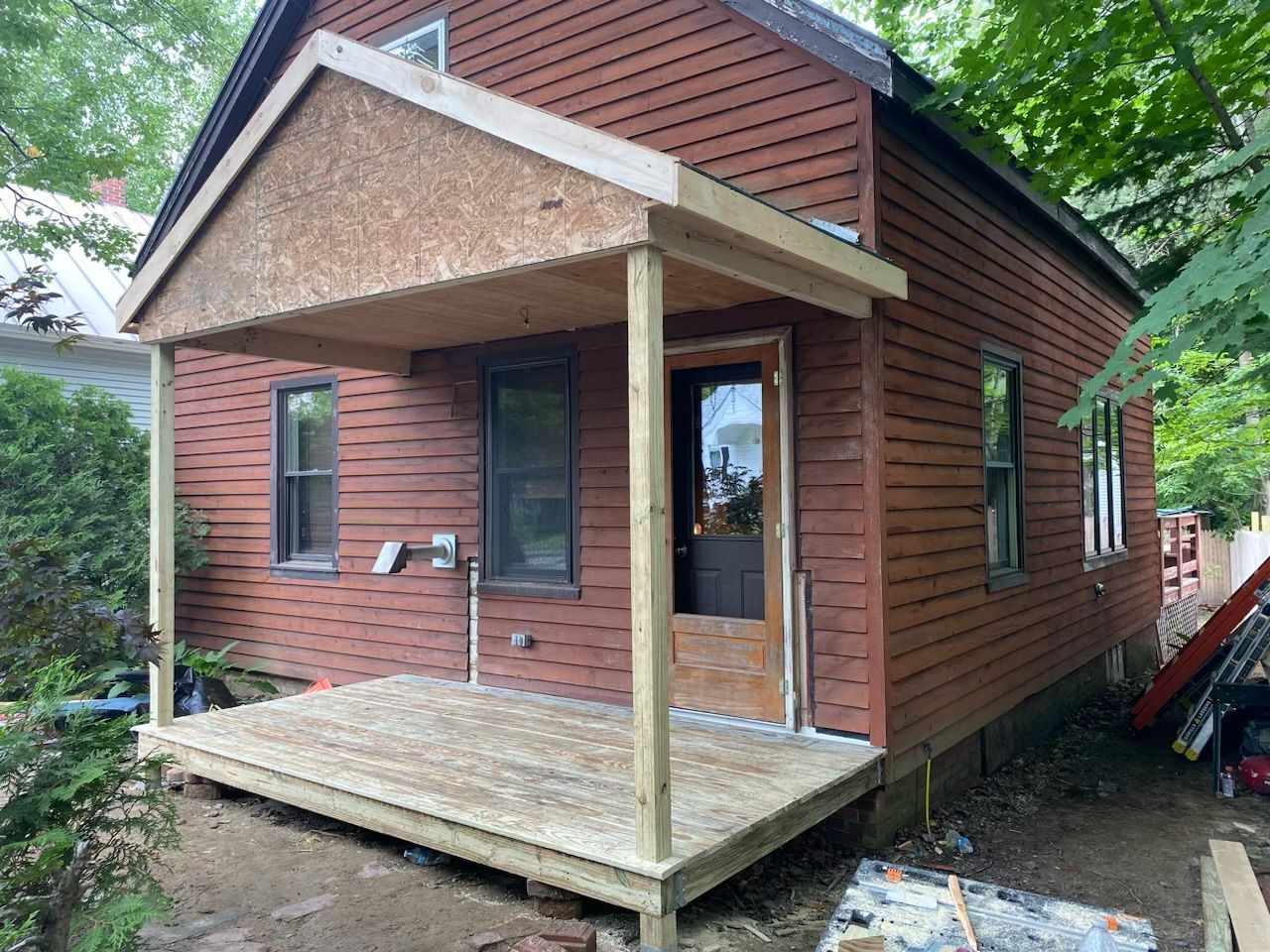 A small house with a porch and a wooden deck.