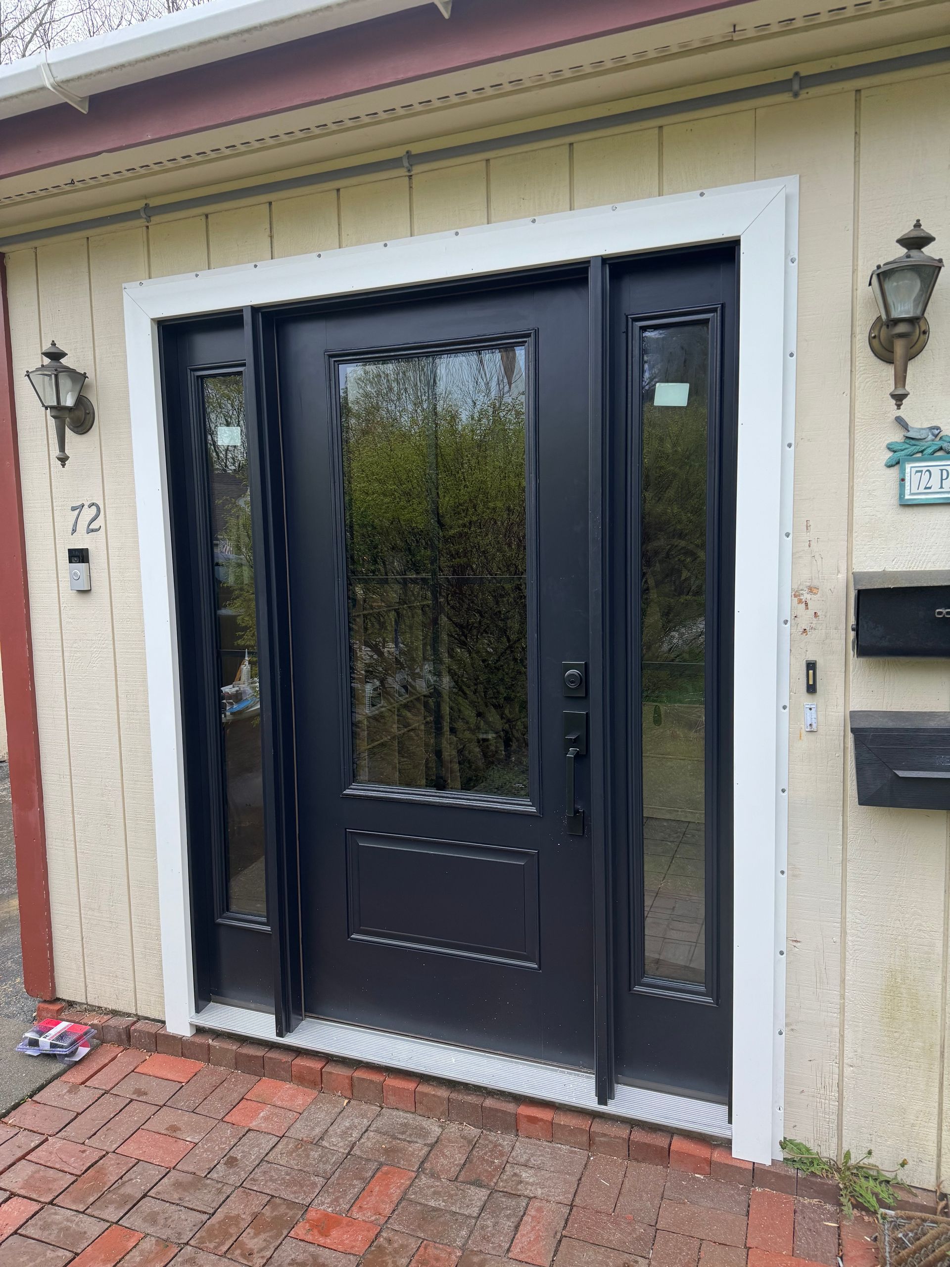 A black door with a white trim is on the front of a house.