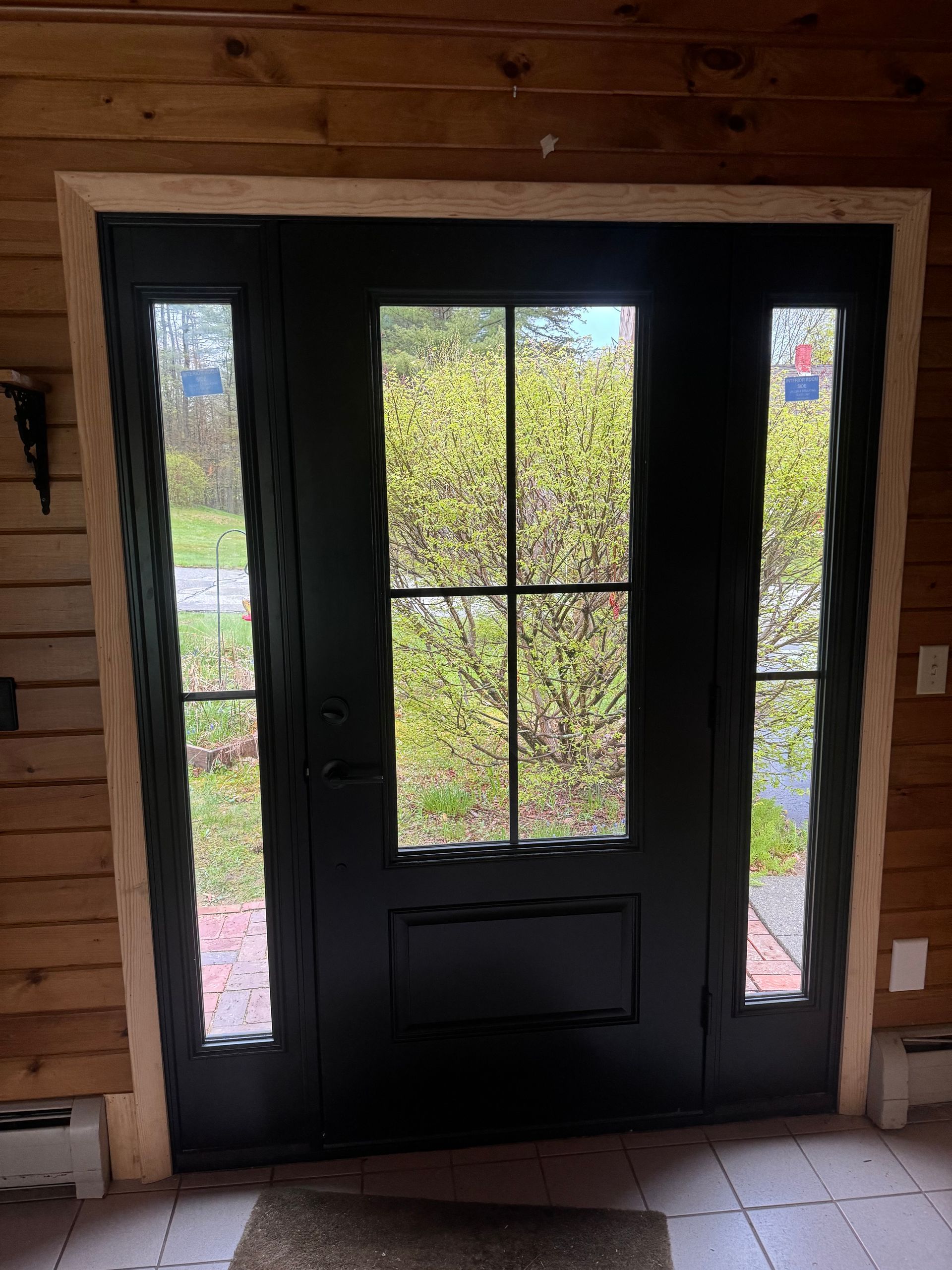 A black door with four windows in a wooden house.