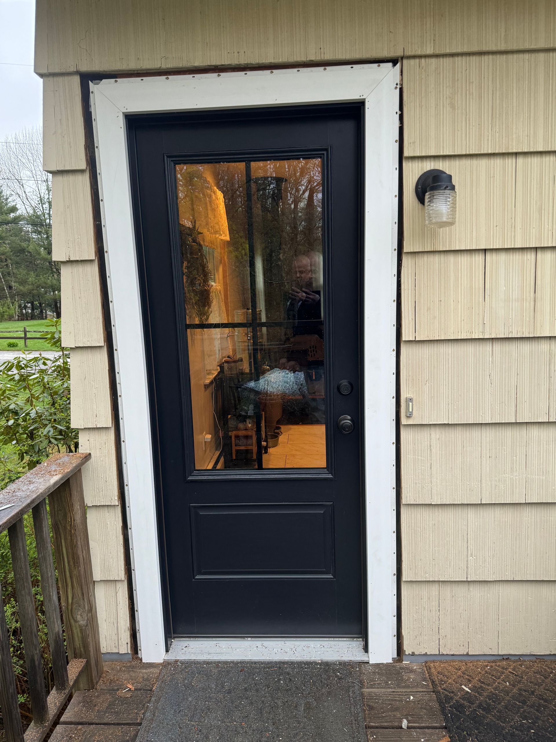A black door with a glass window is on the side of a house.