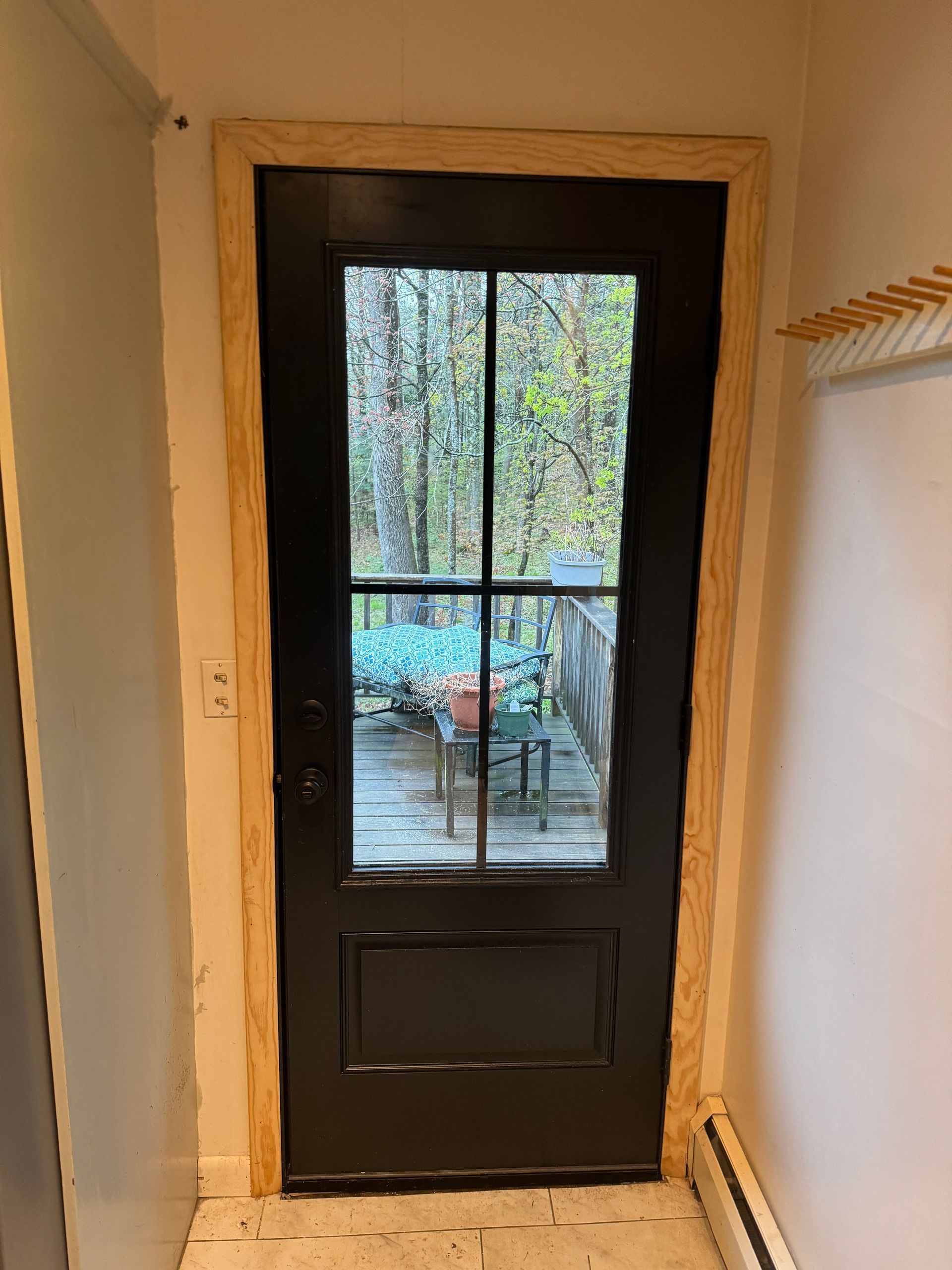 A black door with a glass window in a hallway.