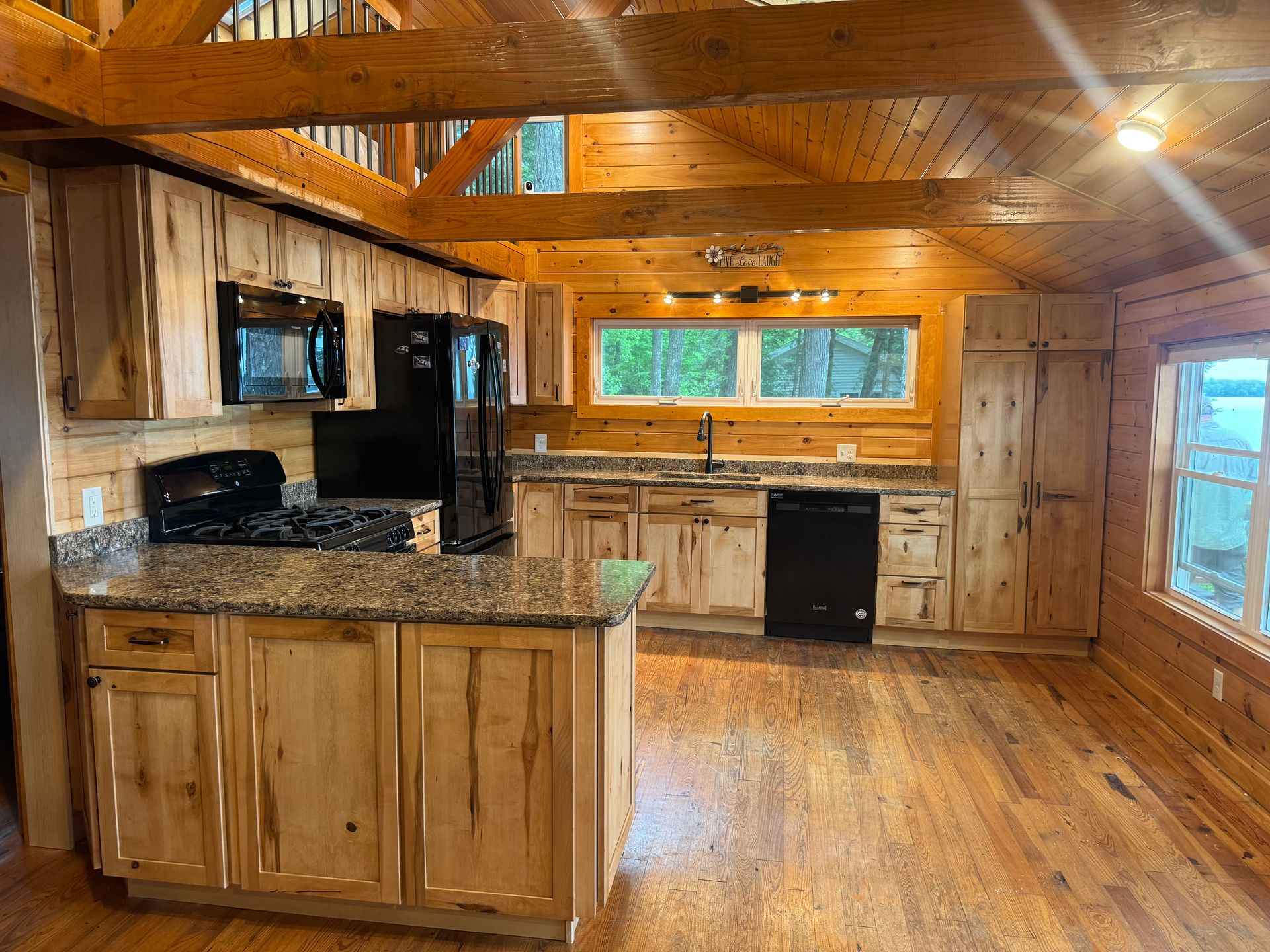 A kitchen in a log cabin with wooden cabinets and granite counter tops.
