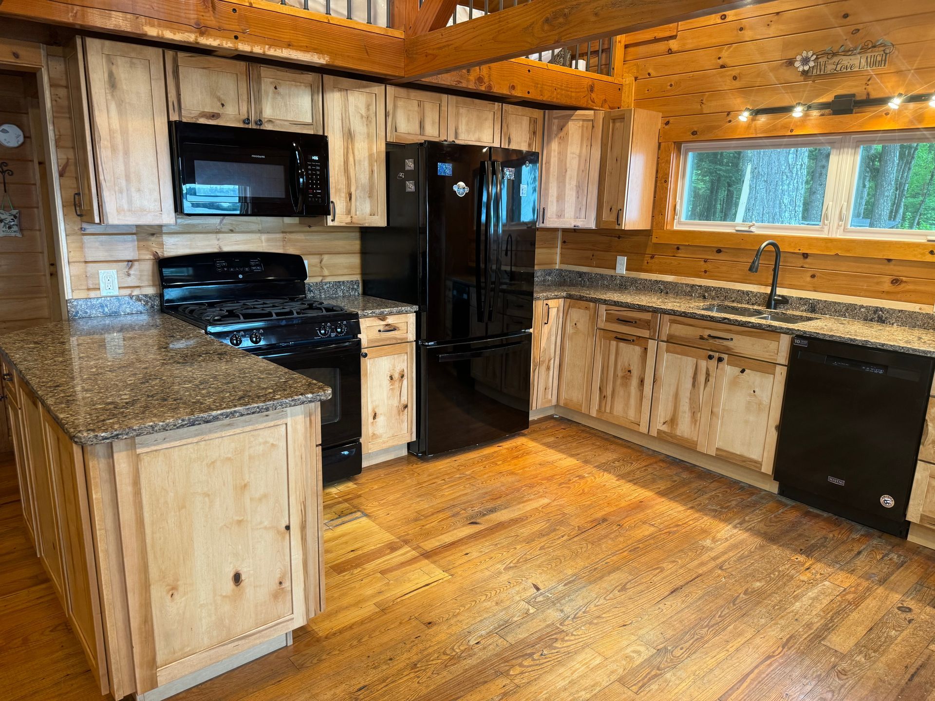 A kitchen in a log cabin with wooden cabinets and granite counter tops.