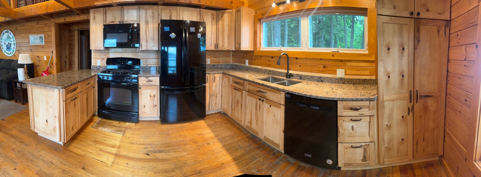 A panoramic view of a kitchen in a log cabin.