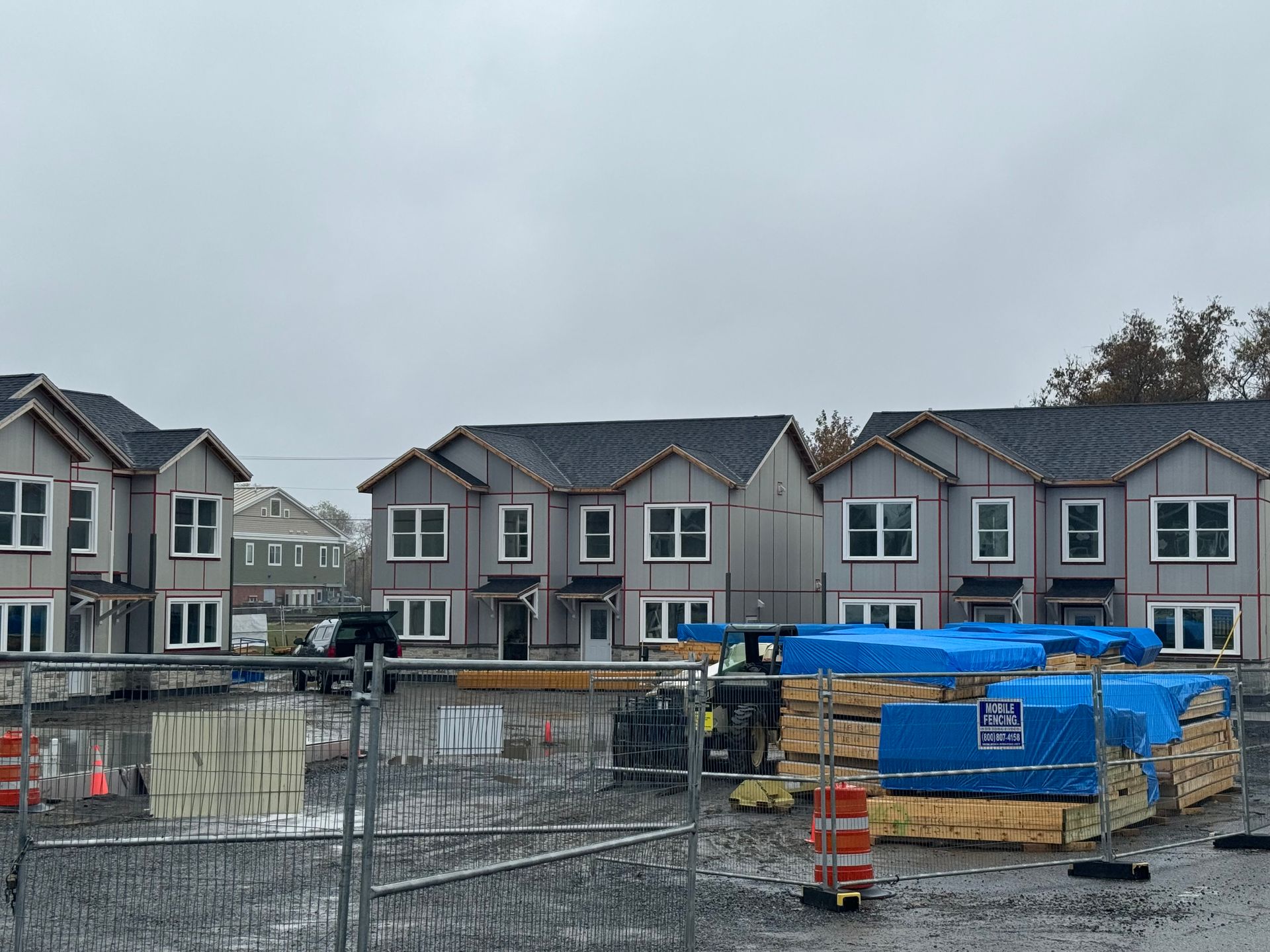 a fence surrounds a row of houses that are being built
