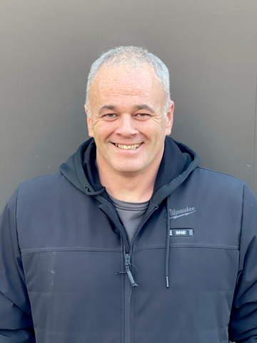 Click here! A professional headshot of a carpenter in a black Milwaukee jacket