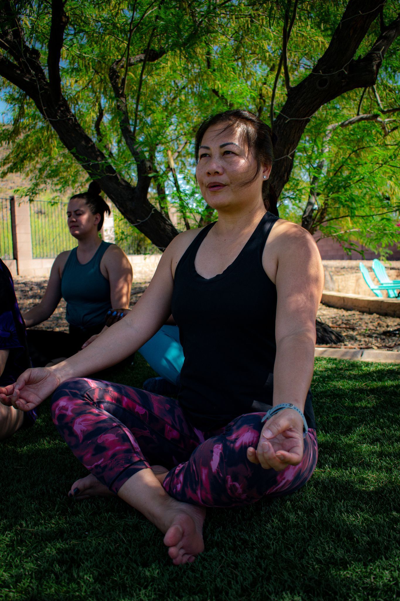 Woman in yoga pose outdoors, other people in background.