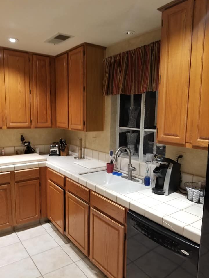 JJR Construction - Kitchen with light brown cabinets, white countertops, and a window above the sink.