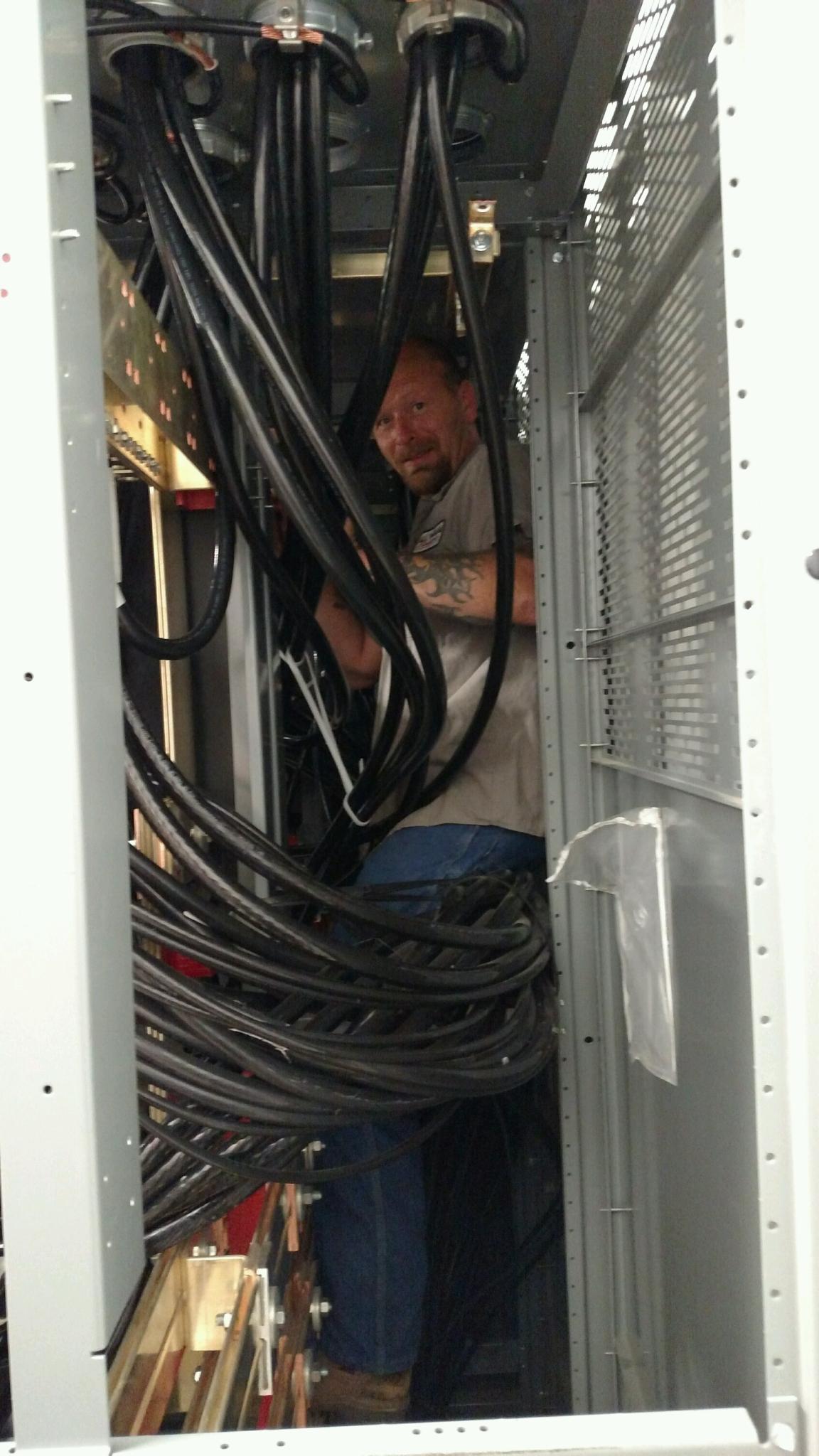 Man working inside a cabinet filled with black cables.