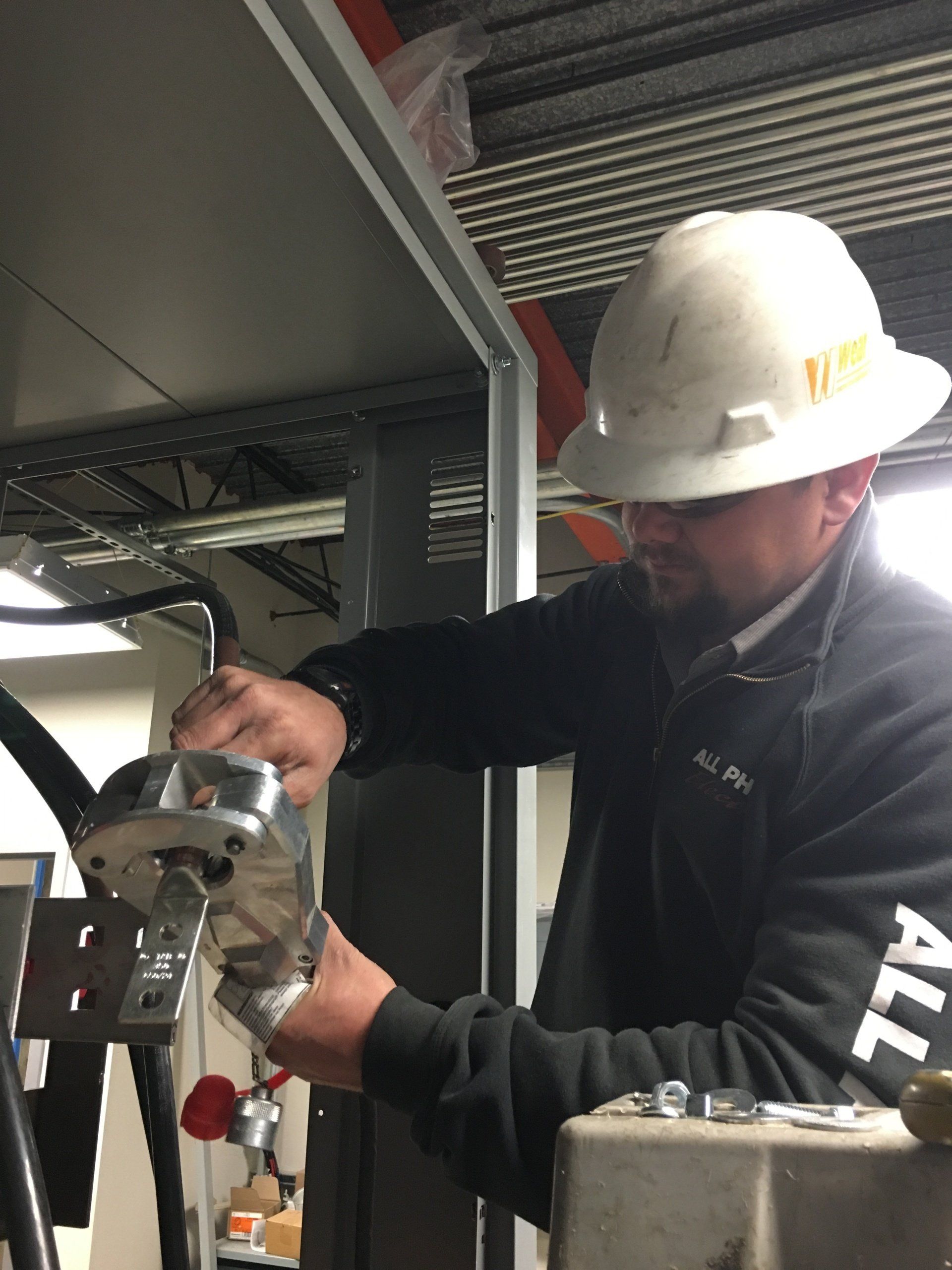 Man in hard hat working on equipment, indoor setting.