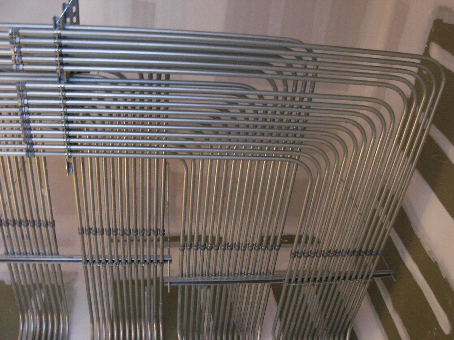 Metal electrical conduits arranged in a grid pattern on a wall.