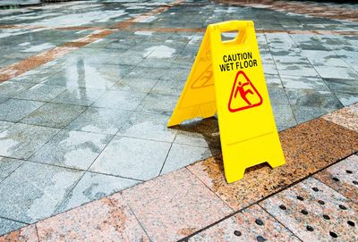 Yellow caution wet floor sign on a wet tiled sidewalk