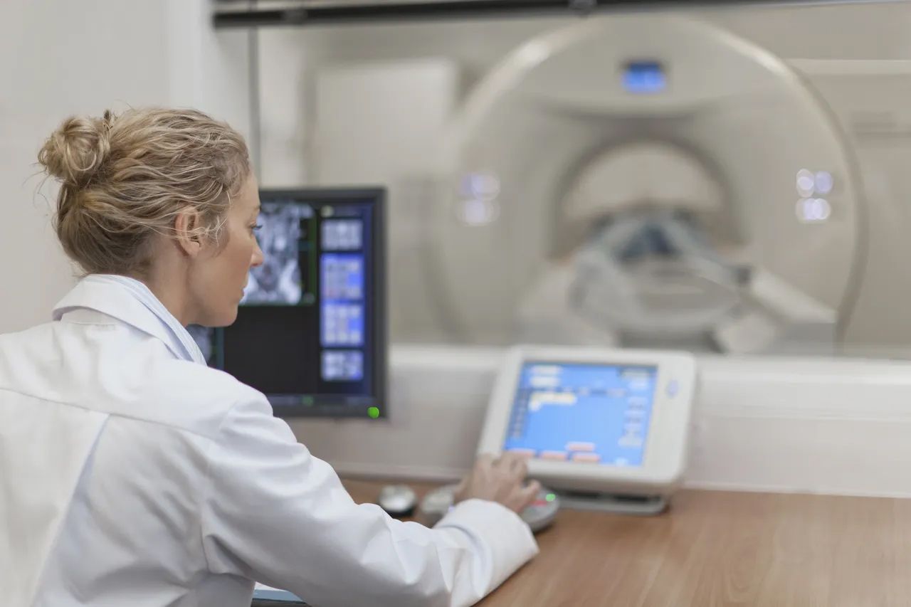 Doctor operating a control panel beside an MRI scanner Doctor operating a control panel beside an MRI scanner