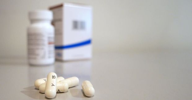 A bottle of pills and a box of pills are on a table.