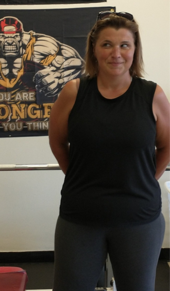A woman stands in front of a poster that says you are strong you thin