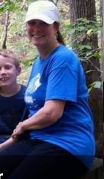 A woman in a blue shirt and white hat is sitting next to a child.