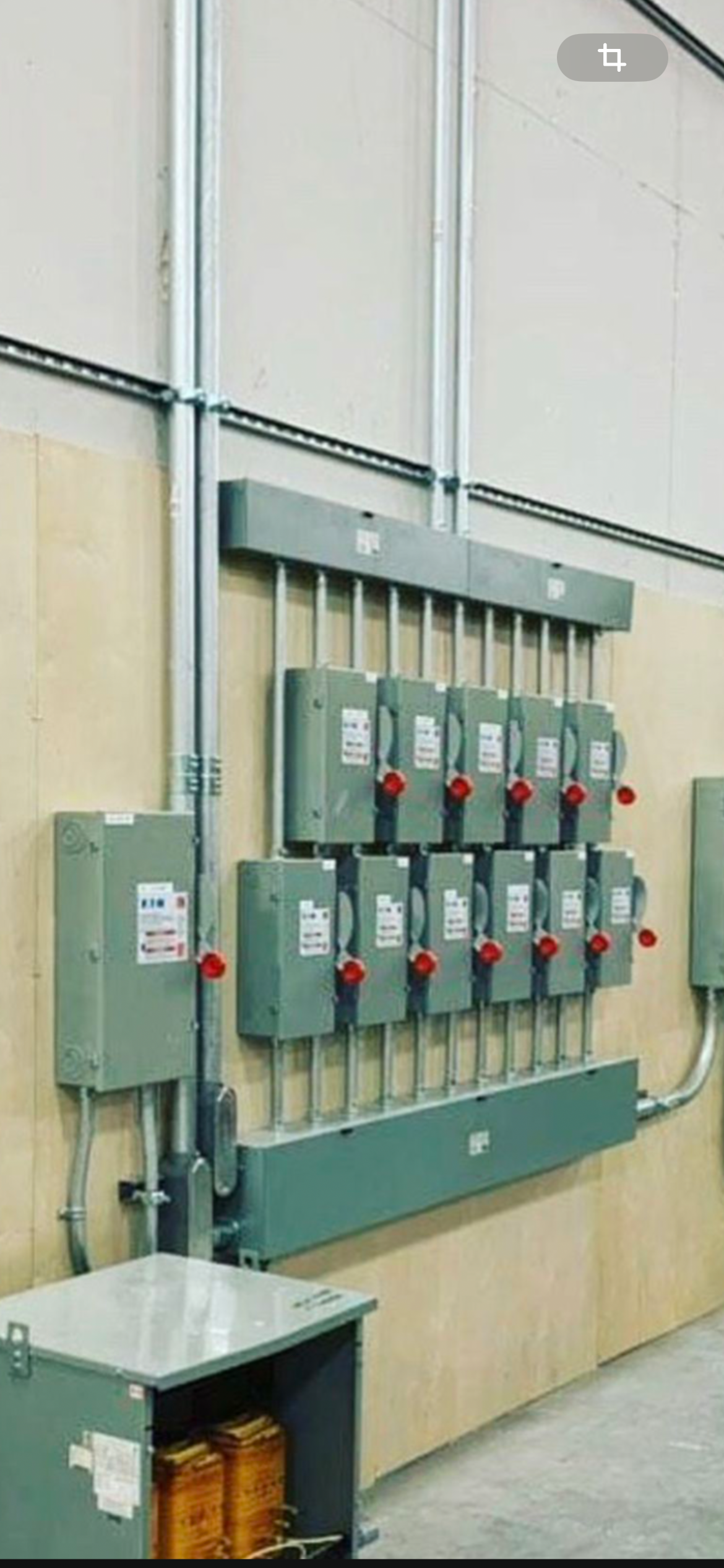 Electrical panel with multiple switches and conduit on a wall.