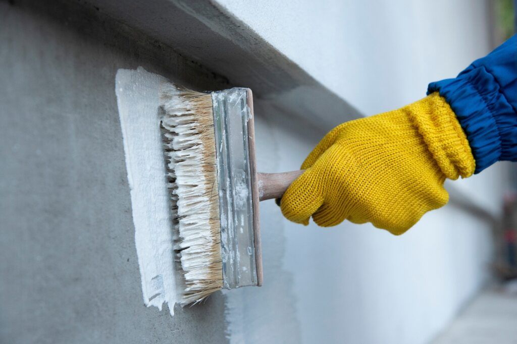 A Person is Painting a Wall With a Brush — A1 Maintenance and Building In Old Bar, NSW