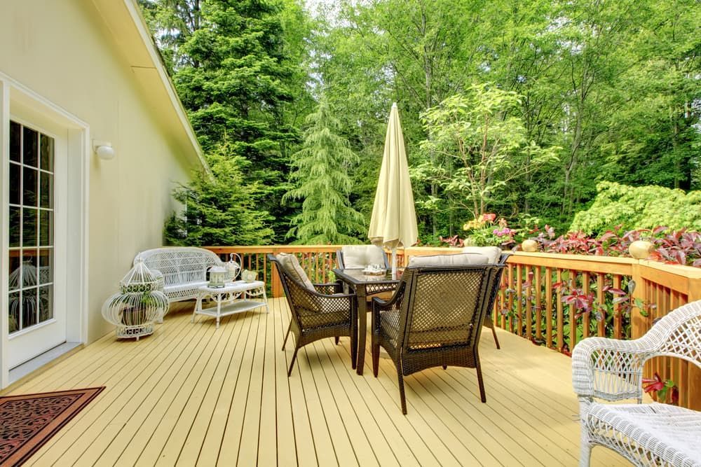 A Wooden Deck With a Table and Chairs and an Umbrella — A1 Maintenance and Building In Old Bar, NSW