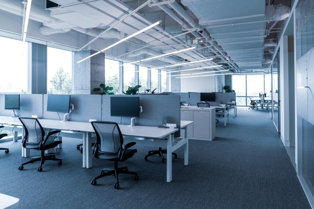 An Empty Office With a Lot of Windows and Desks and Chairs — A1 Maintenance and Building In Old Bar, NSW