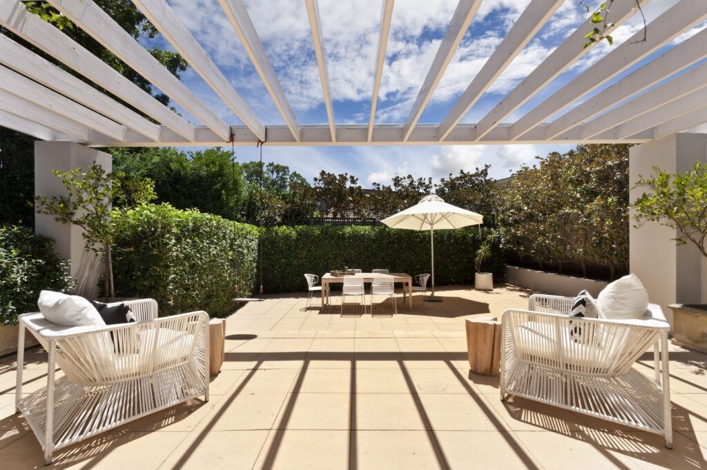 A Patio With Chairs and a Table Under a Pergola — A1 Maintenance and Building In Old Bar, NSW