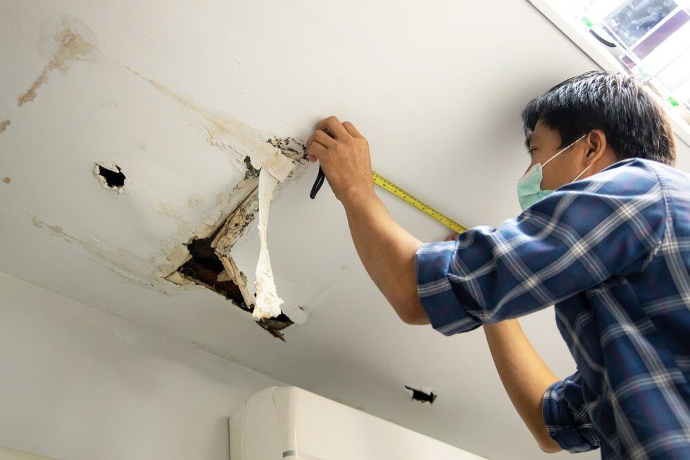 A Man is Measuring a Ceiling With a Tape Measure — A1 Maintenance and Building In Old Bar, NSW