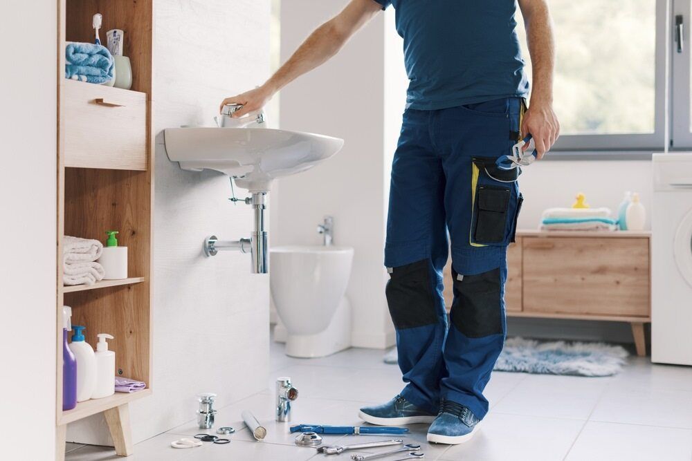 A Plumber is Fixing a Sink in a Bathroom — A1 Maintenance and Building In Old Bar, NSW