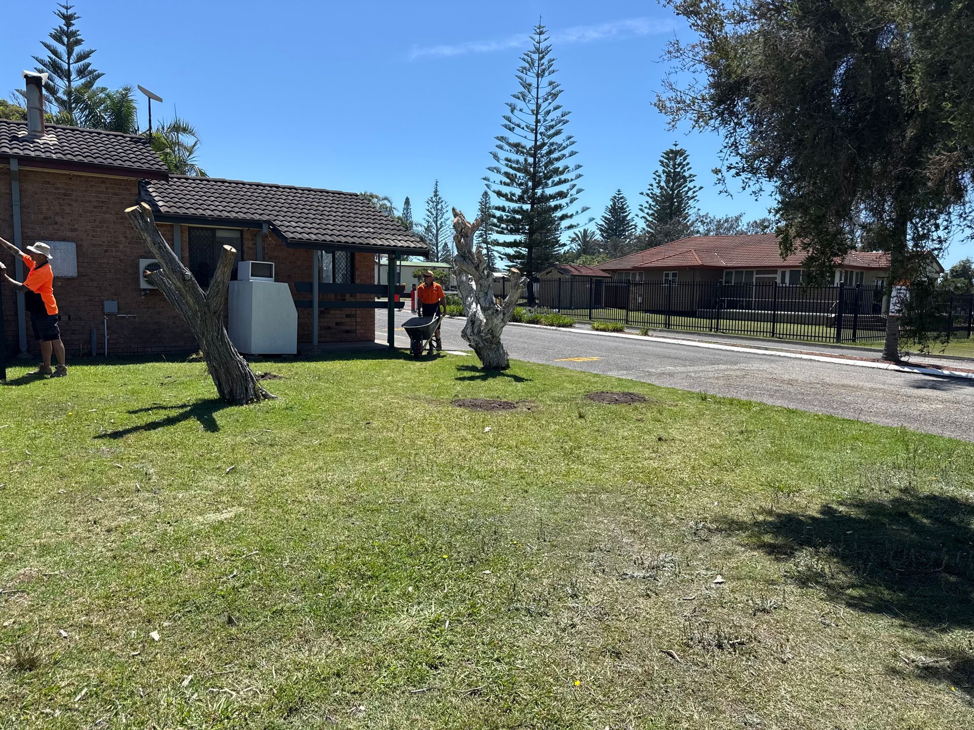People working near buildings on a sunny day. Green grass and trees in foreground. - A1 Maintenance and Building In Old Bar, NSW