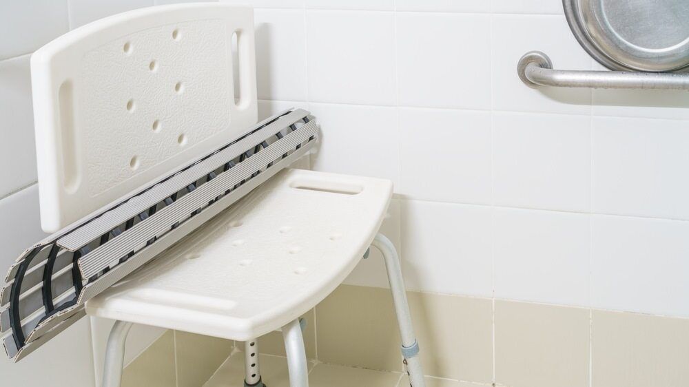 A White Bath Chair is Sitting Next to a Bathtub in a Bathroom — A1 Maintenance and Building In Forster, NSW