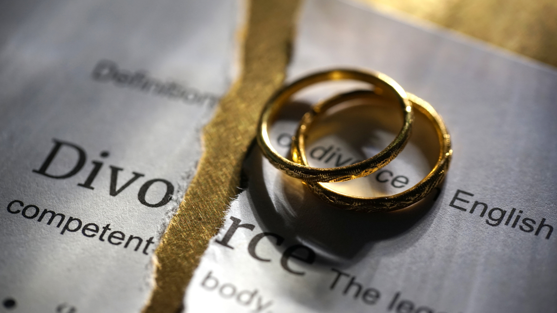 Two wedding rings are sitting on top of a dictionary page that says divorce
