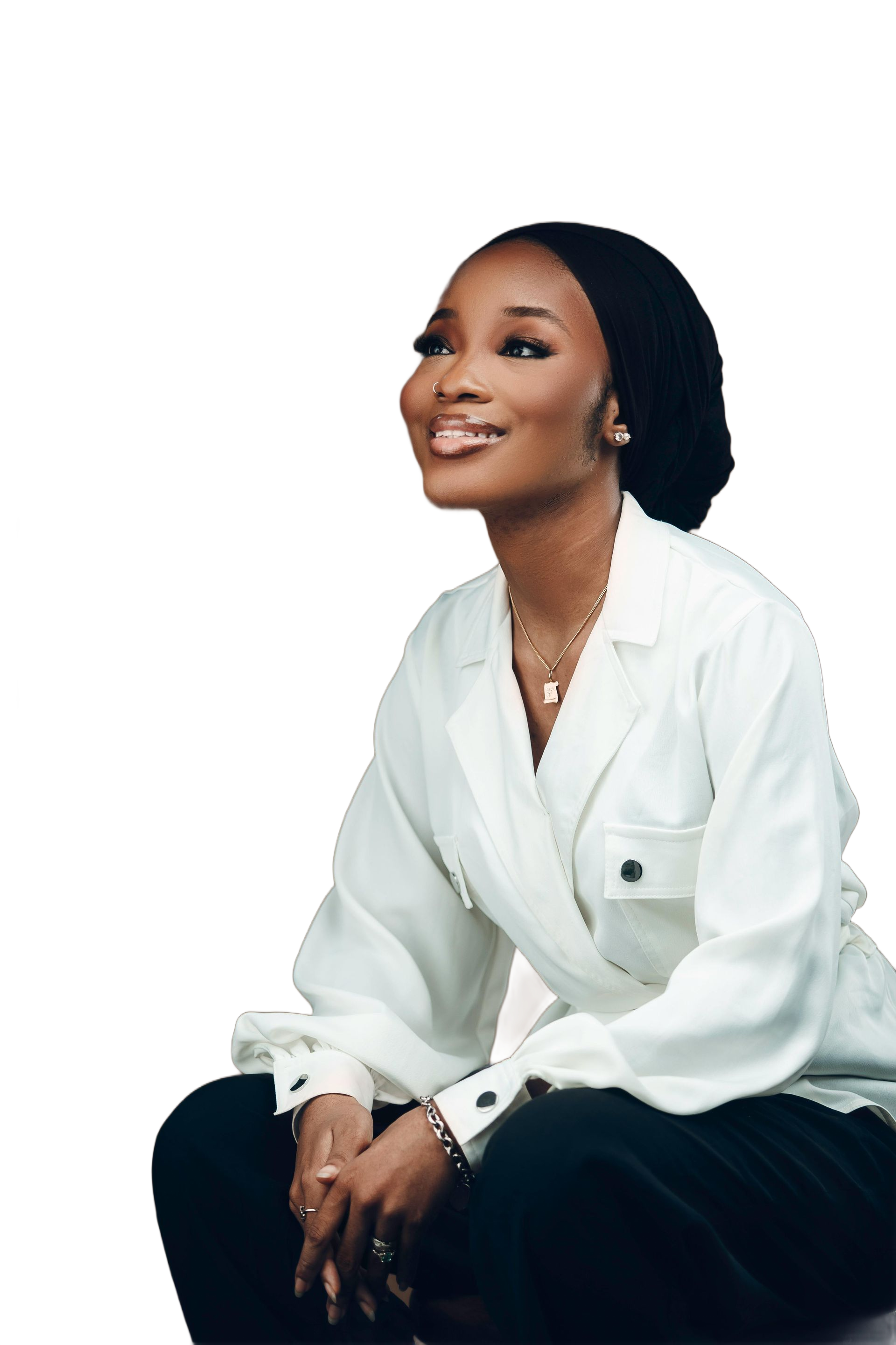 Woman in white jacket and black head wrap smiles, looking up and to the right.
