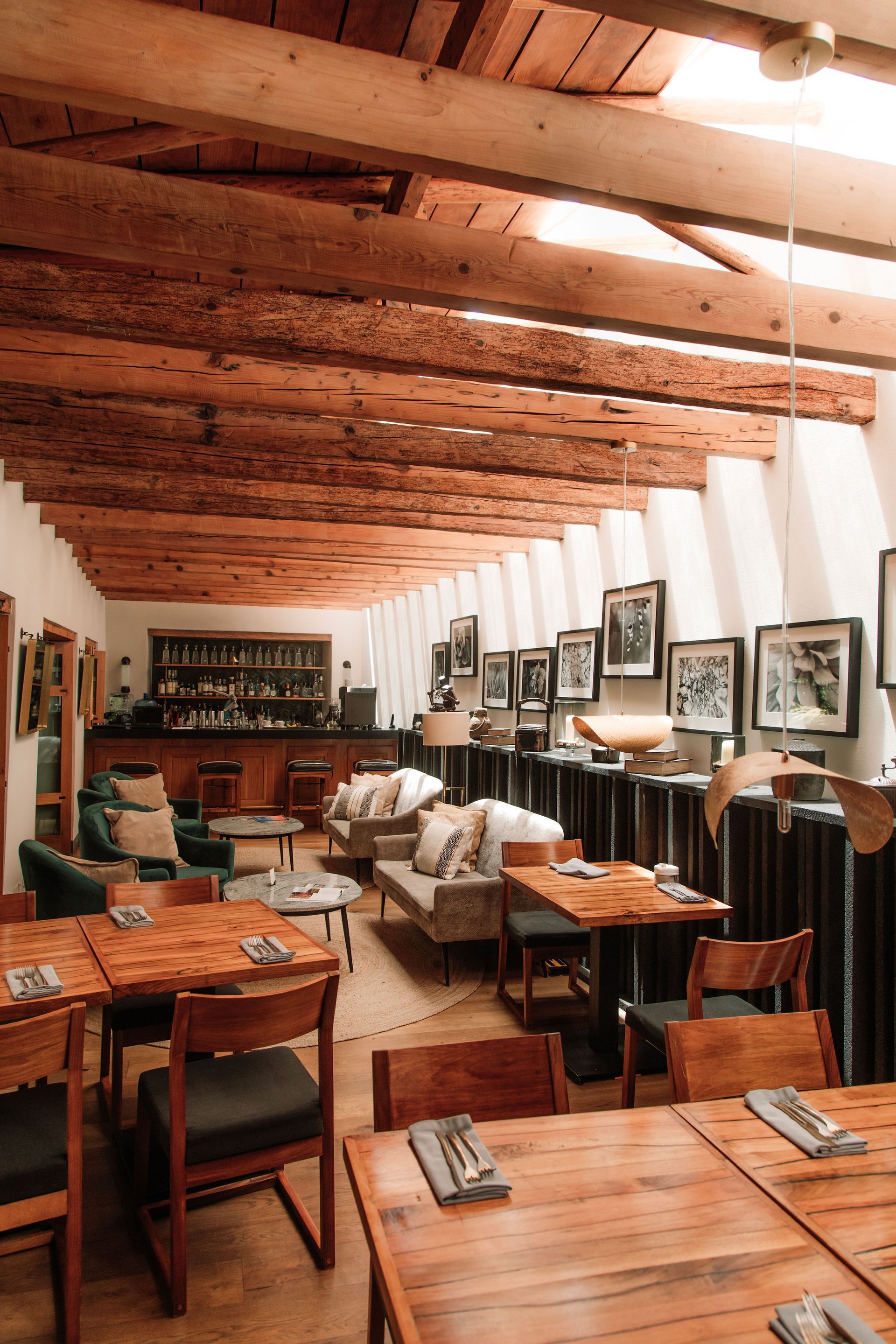 Restaurante con vigas de madera, mesas, cuadros y un radiador largo a lo largo de la pared.