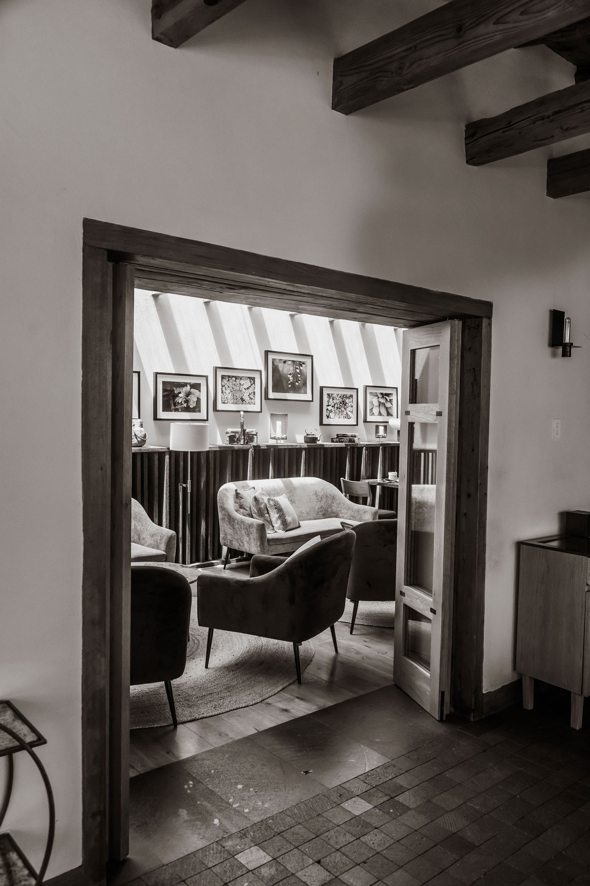 Acogedora sala de estar vista a través de una puerta, con sillones, un sofá, fotos enmarcadas y vigas de madera.