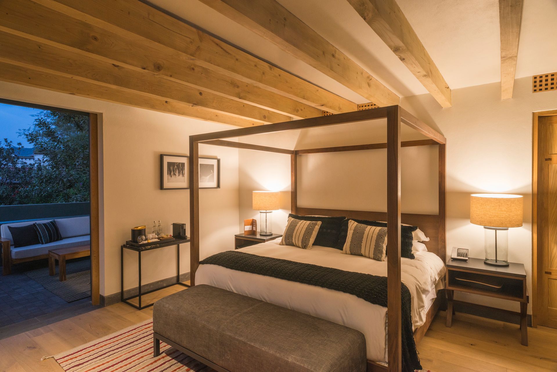 Habitación acogedora con cama con dosel, iluminación cálida y balcón abierto con vistas.