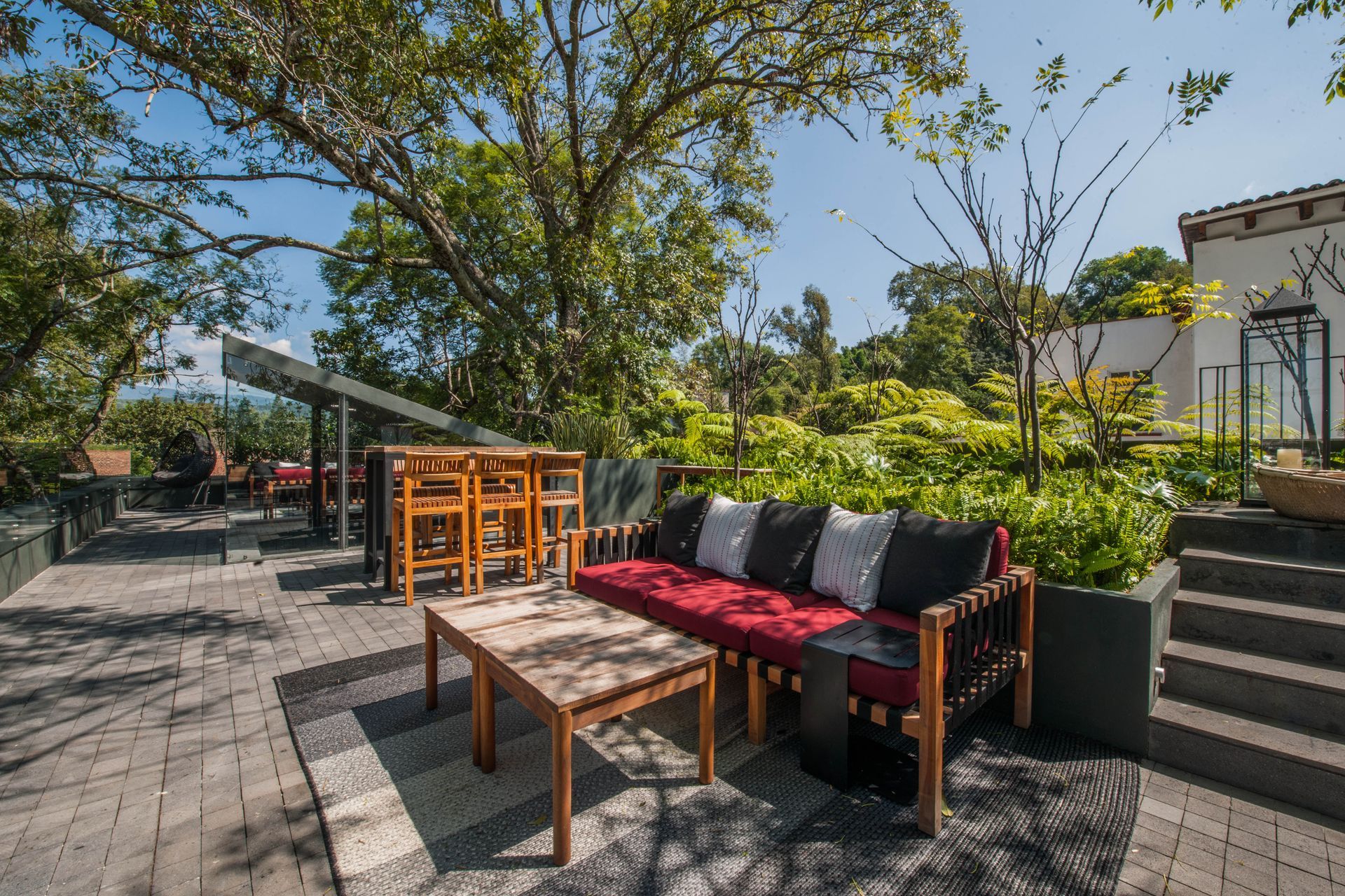 Rooftop con vista al centro. Salas exteriores con muebles rojo y negro, periqueras y escaleras al jacuzzi.