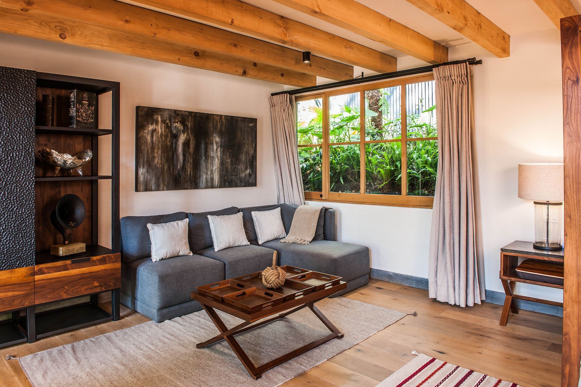 Amplia sala interior de la suite cinco, con sofá gris mesa de madera y piel, armario oscuro y piezas de arte únicas