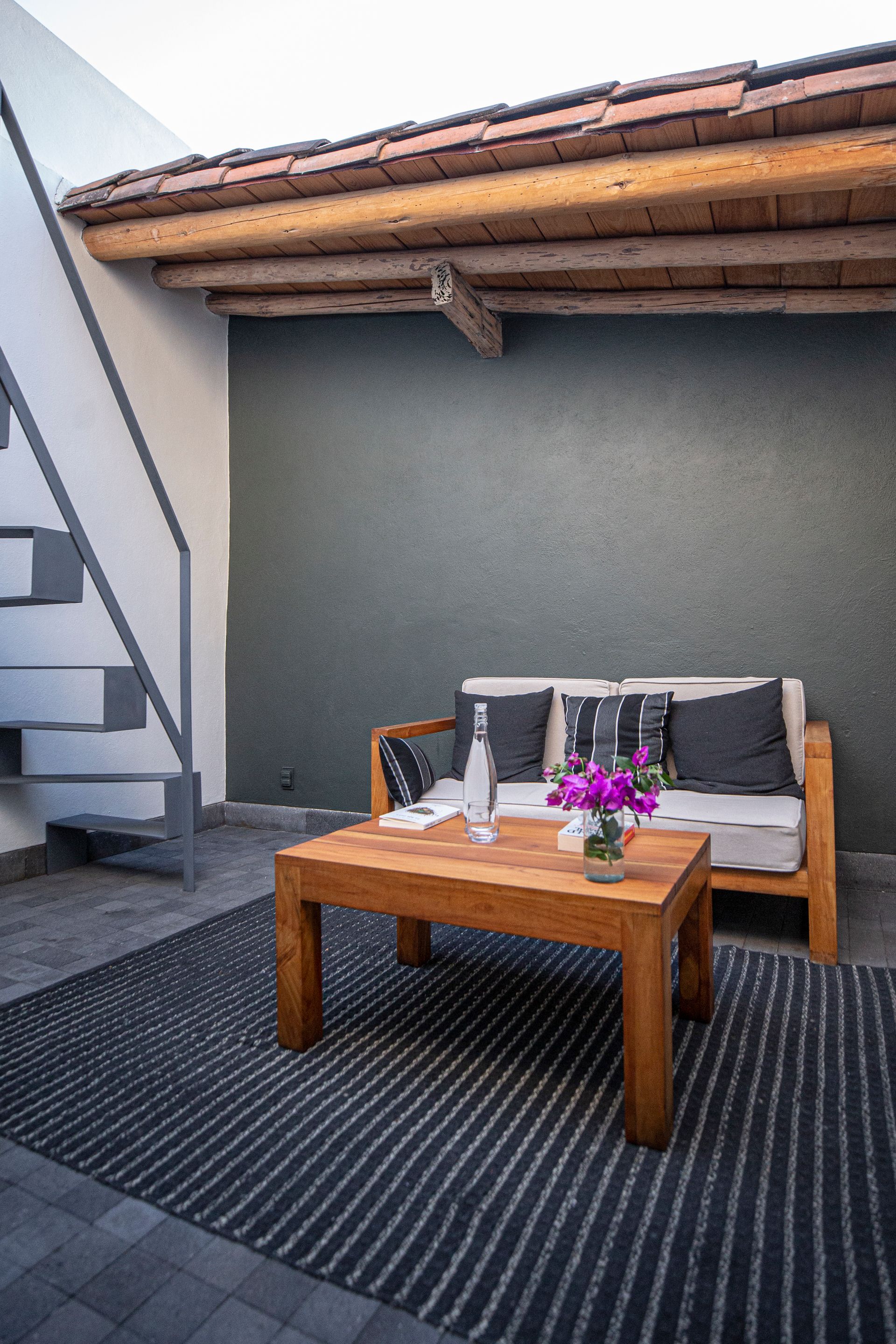 Patio interior privado de la suite dos, con sillón y escalera para acceder al rooftop privado de la suite dos