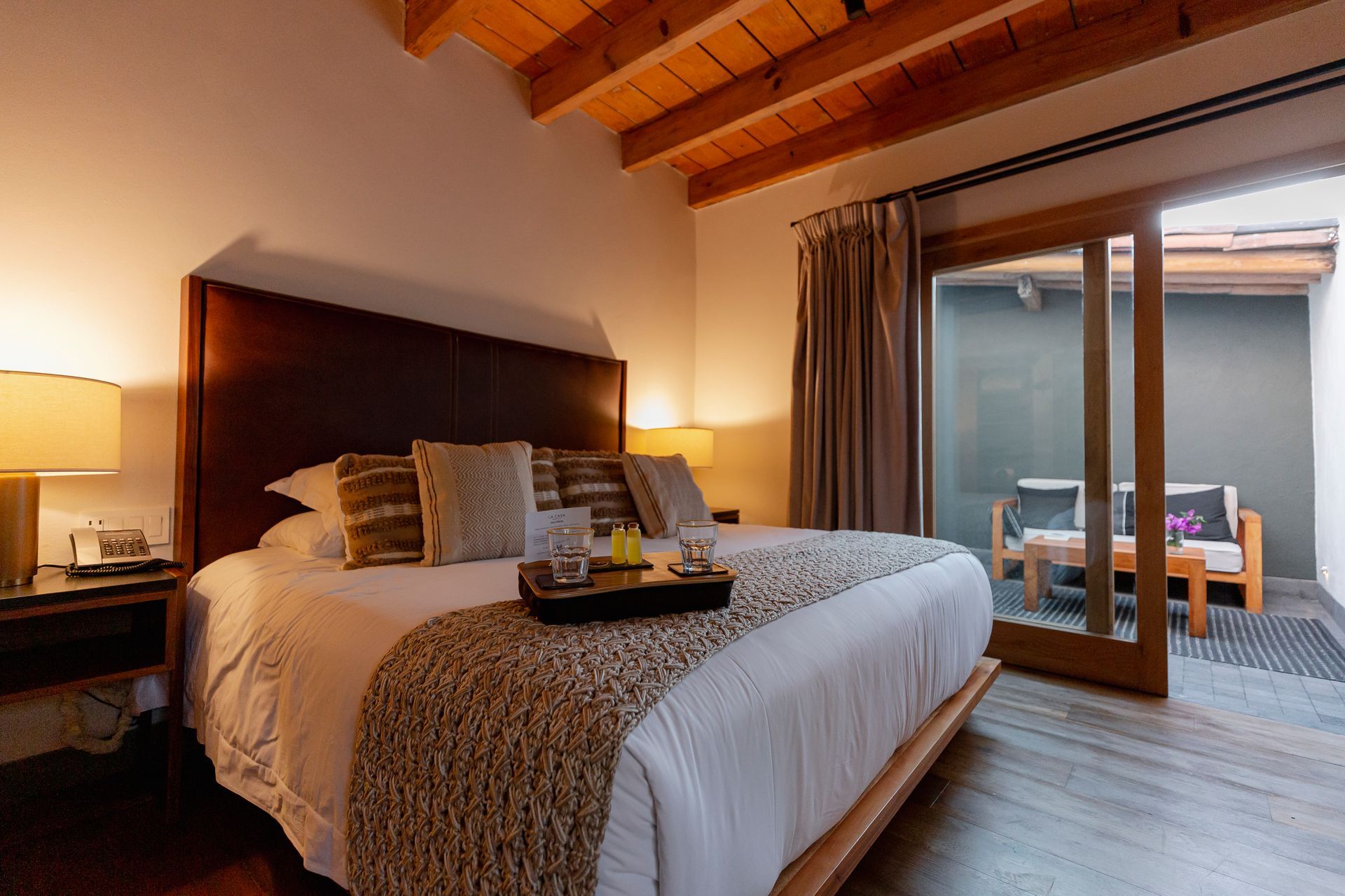 Habitación acogedora con cama de madera, lámparas y puertas correderas que dan a un patio.