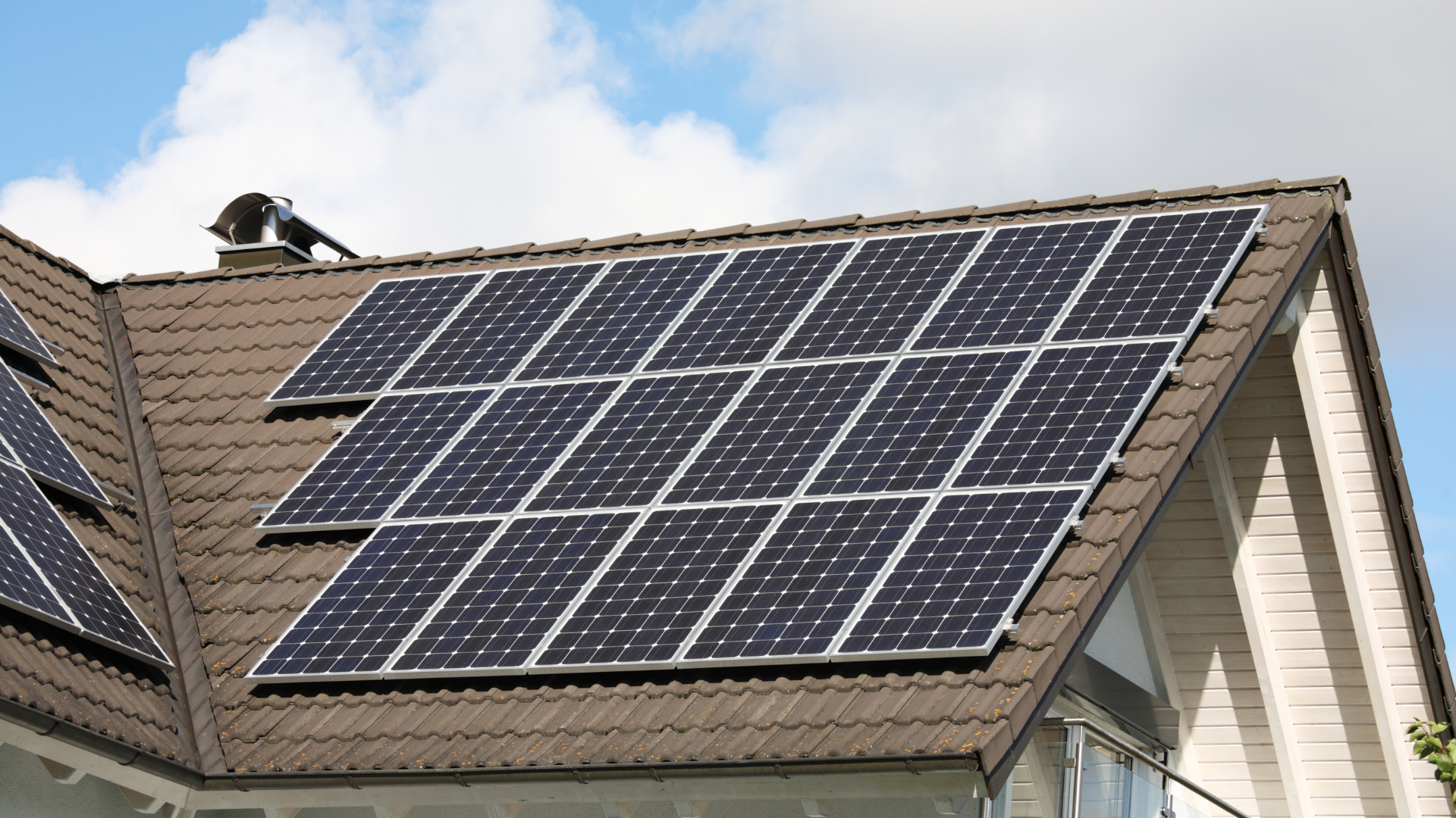 There are many solar panels on the roof of a house.