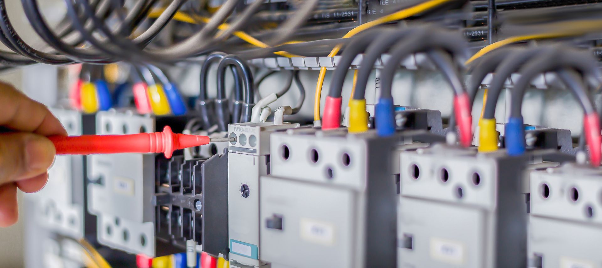 A person is working on an electrical panel with a screwdriver.