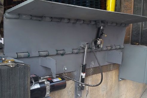 A hydraulic ramp is attached to the side of a building.
