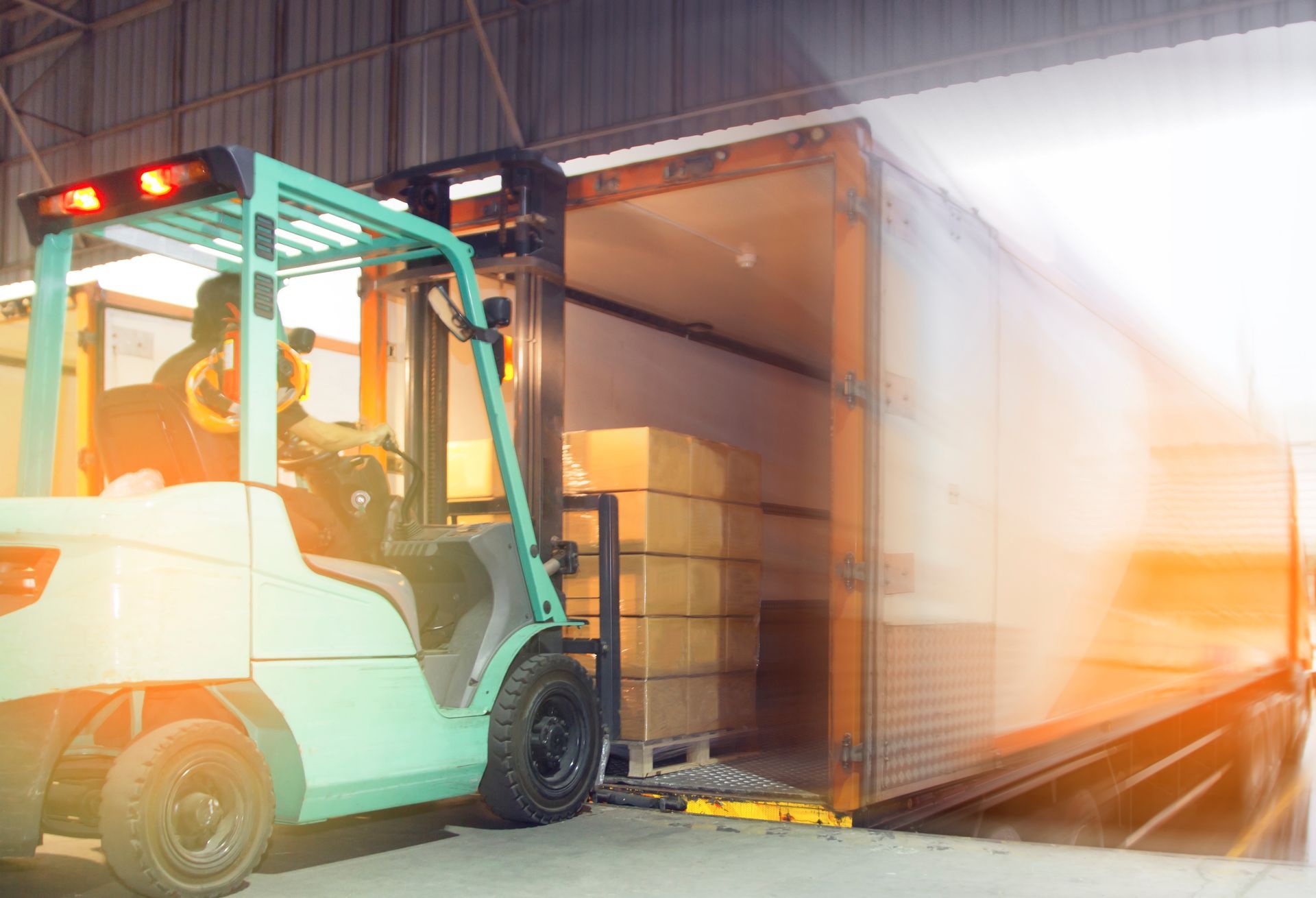 Un chariot élévateur charge des cartons dans un semi-remorque dans un entrepôt.