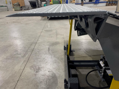 Une rampe métallique est posée sur un sol en béton dans un entrepôt.