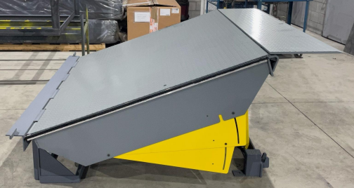 Une machine grise et jaune est posée sur un sol en béton.