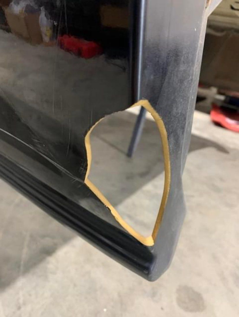 Black car bumper with a jagged, missing section, revealing a tan interior.