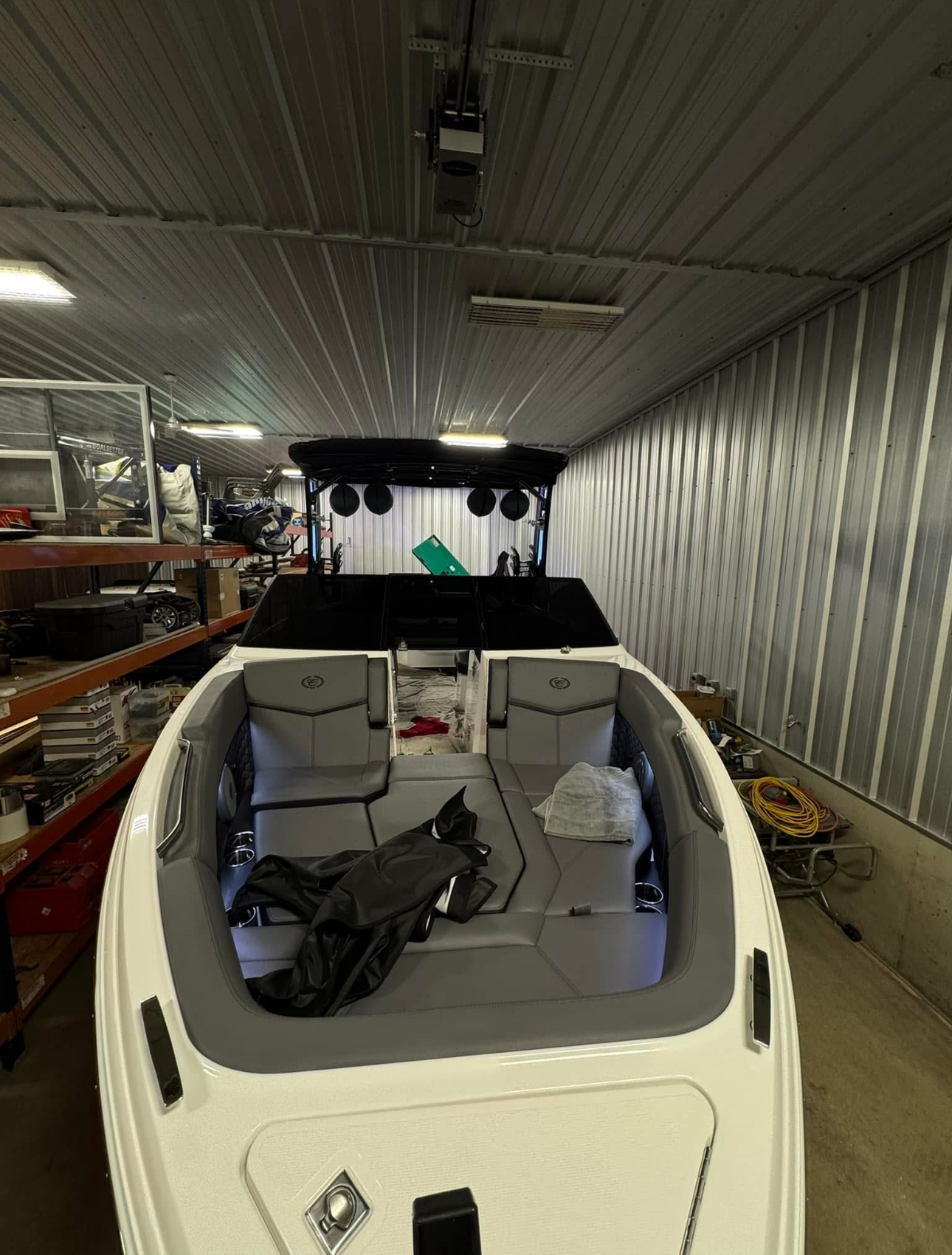 White boat interior with gray seats and a black sunshade in a workshop.